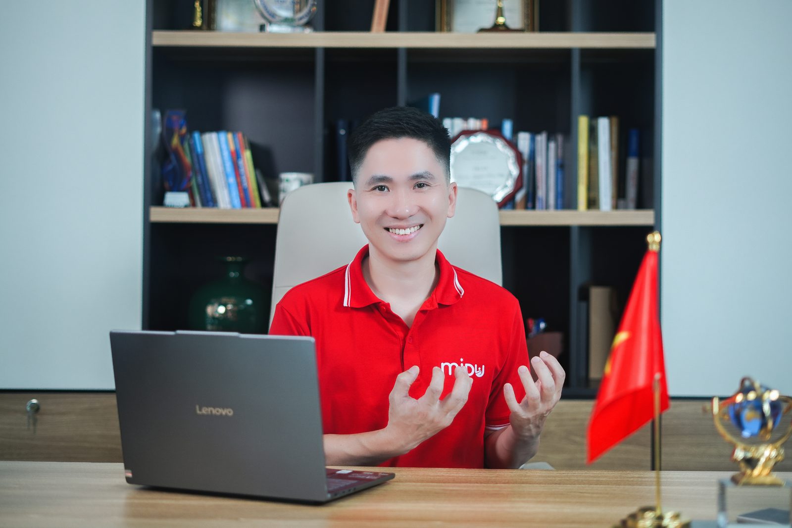 Nguyễn Xuân Hợp ngồi bàn làm việc, hai tay mở ra như đang giảng giải